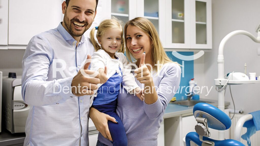 A happy family, including a mother, father, and daughter, smiling and giving a thumbs-up at R&G Dental clinic, showcasing a positive and family-friendly dental experience.